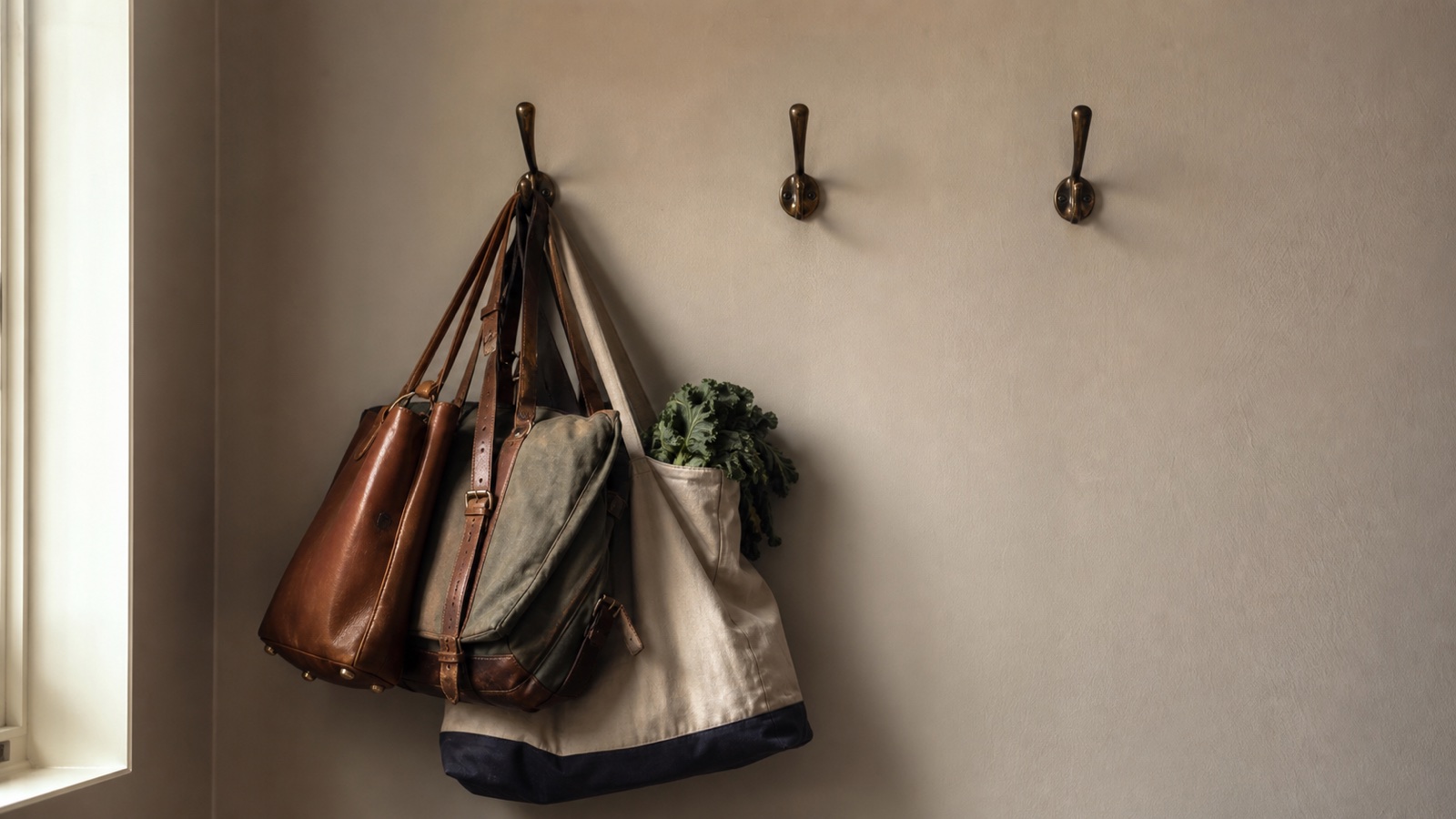 Several heavy work and household bags crowded onto one hook beside two empty hooks